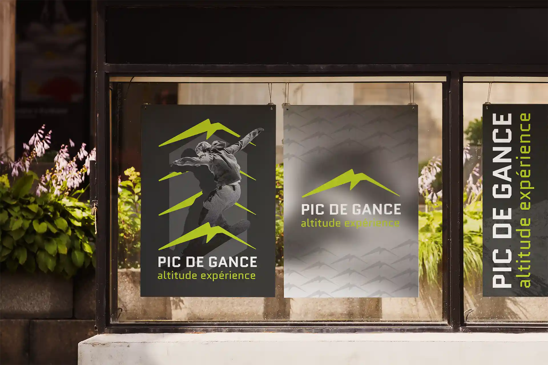 Trois affiches Pic de Gance "altitude expérience" en vitrine d'une boutique, logo montagne stylisé vert et skieur en action