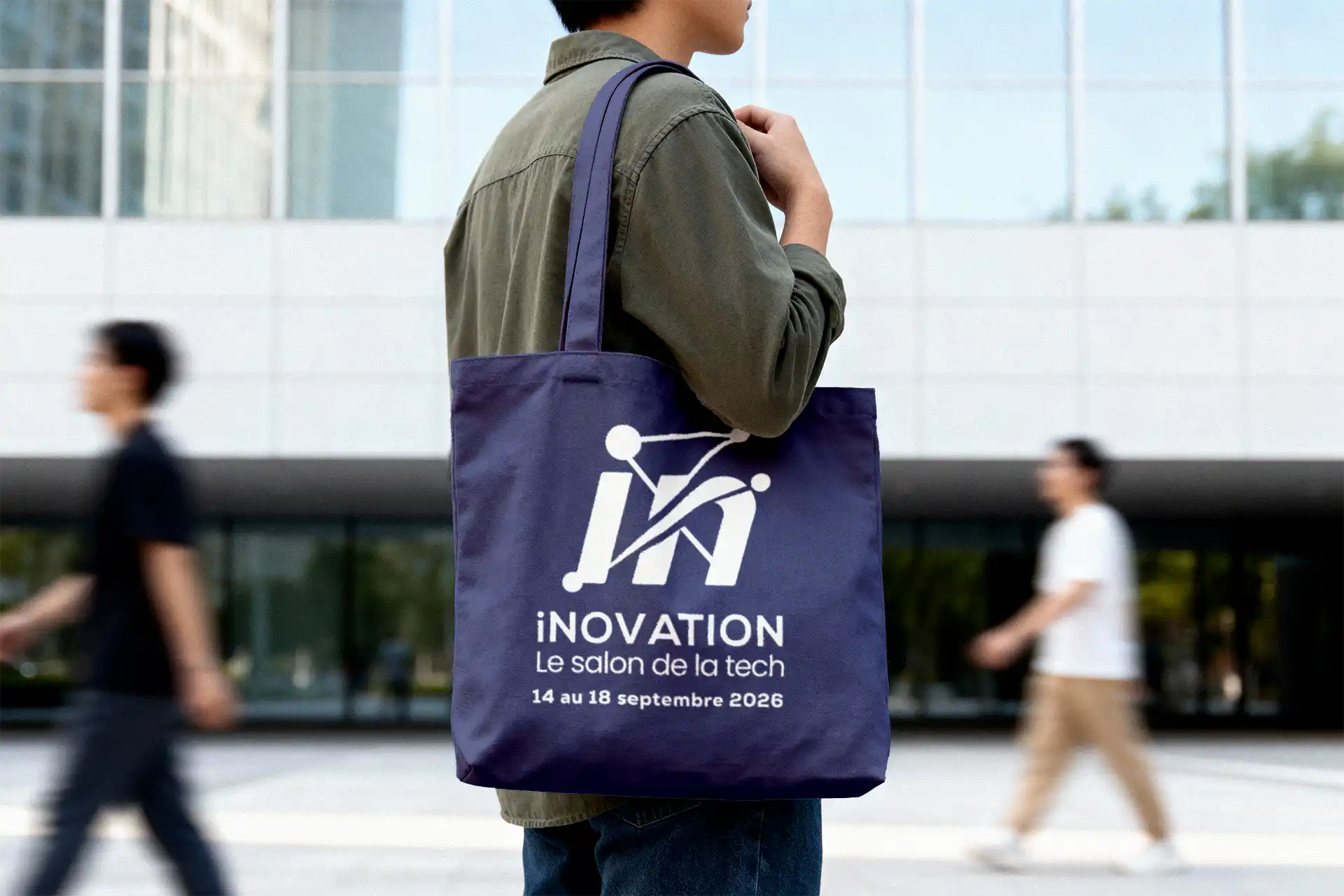 Tote bag bleu marine iNOVATION porté à l'épaule dans un contexte urbain, logo salon de la tech et dates 14-18 septembre 2026